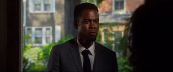 Movie still from “Spiral” (2021), directed by Darren Lynn Bousman – A man wearing a suit and tie in front of a building; Close Up shot, Over the shoulder angle