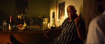 Movie still from “Spiral” (2021), directed by Darren Lynn Bousman – A man sitting on a chair in a room; Medium shot, Low angle