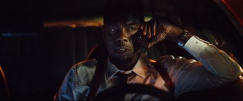 Movie still from “Spiral” (2021), directed by Darren Lynn Bousman – A man in a car talking on a cell phone; Close Up shot, Low angle