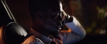 Movie still from “Spiral” (2021), directed by Darren Lynn Bousman – A person wearing a suit and tie; Close Up shot, Low angle