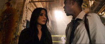 Movie still from “Spiral” (2021), directed by Darren Lynn Bousman – A woman standing next to a man wearing a tie; Close Up shot, Over the shoulder angle