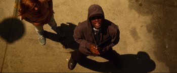 Movie still from “Spiral” (2021), directed by Darren Lynn Bousman – A man sitting on the ground holding a cell phone; Medium shot, Overhead angle