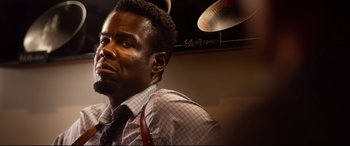 Movie still from “Spiral” (2021), directed by Darren Lynn Bousman – A man in a dress shirt and a tie looking to his left; Close Up shot, Low angle