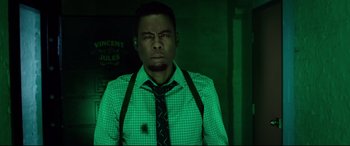 Movie still from “Spiral” (2021), directed by Darren Lynn Bousman – A man wearing a green tie and a white shirt; Medium shot, Low angle