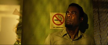 Movie still from “Spiral” (2021), directed by Darren Lynn Bousman – A man standing in front of a no smoking sign; Close Up shot, Low angle