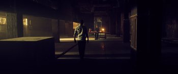 Movie still from “Spiral” (2021), directed by Darren Lynn Bousman – A man walking in the dark in a building; Extreme Wide shot, Low angle