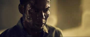 Movie still from “Spiral” (2021), directed by Darren Lynn Bousman – A man's face in a dimly - lit room; Extreme Close Up shot, Low angle