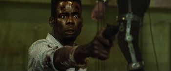 Movie still from “Spiral” (2021), directed by Darren Lynn Bousman – A man holding a gun in a room; Close Up shot, Low angle