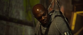 Movie still from “Spiral” (2021), directed by Darren Lynn Bousman – A bald man wearing headphones and looking down; Close Up shot, Low angle