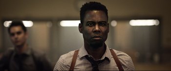 Movie still from “Spiral” (2021), directed by Darren Lynn Bousman – A man wearing a plaid shirt and suspenders looks at the camera; Close Up shot, Low angle