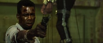 Movie still from “Spiral” (2021), directed by Darren Lynn Bousman – A man holding a gun while standing next to another man; Close Up shot, Low angle