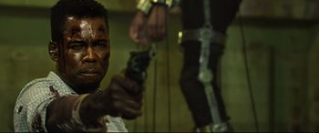 Movie still from “Spiral” (2021), directed by Darren Lynn Bousman – A man holding a gun while standing next to another man in chains; Close Up shot, Over the shoulder angle