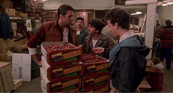 Movie still from “Splash” (1983), directed by Ron Howard – A group of men standing around a pile of cherries; Medium shot, High angle