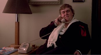 Movie still from “Splash” (1983), directed by Ron Howard – A man sitting on a chair talking on a phone; Medium shot, Low angle