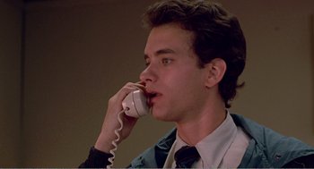 Movie still from “Splash” (1983), directed by Ron Howard – A young man talking on a phone while wearing a suit and tie; Close Up shot, Low angle