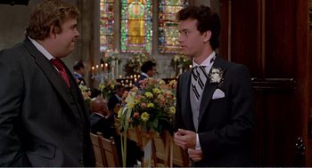 Movie still from “Splash” (1983), directed by Ron Howard – A man in a suit talking to another man in front of a stained glass window; Medium shot, Over the shoulder angle