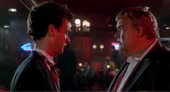 Movie still from “Splash” (1983), directed by Ron Howard – Two men in business suits are talking in a bar; Close Up shot, Over the shoulder angle