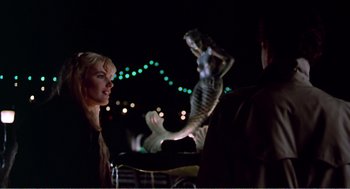 Movie still from “Splash” (1983), directed by Ron Howard – A woman standing next to a statue of a mermaid; Medium shot, Over the shoulder angle