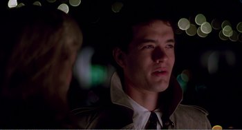 Movie still from “Splash” (1983), directed by Ron Howard – A man wearing a jacket and tie in a dark room; Close Up shot, Over the shoulder angle