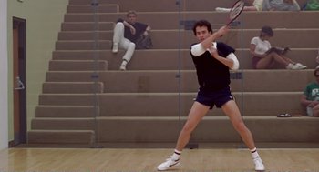 Movie still from “Splash” (1983), directed by Ron Howard – A man swinging a tennis racquet on top of a court; Wide shot, Low angle