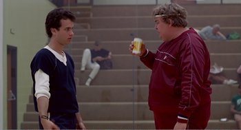 Movie still from “Splash” (1983), directed by Ron Howard – Two men standing next to each other in front of stairs; Medium shot, Over the shoulder angle