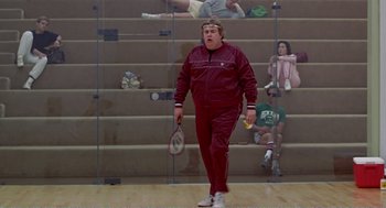 Movie still from “Splash” (1983), directed by Ron Howard – A man holding a racquet while standing on a court; Wide shot, Low angle
