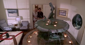 Movie still from “Splash” (1983), directed by Ron Howard – Two people standing in front of a fountain in a living room; Wide shot, High angle