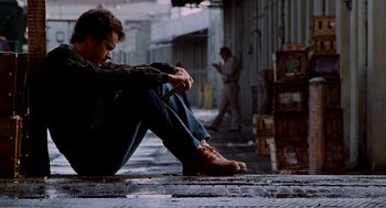 Movie still from “Splash” (1983), directed by Ron Howard – A man sitting on the ground with his feet on the ground; Wide shot, Low angle