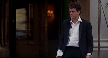 Movie still from “Splash” (1983), directed by Ron Howard – A man in a suit and tie standing in front of a building; Medium shot, Over the shoulder angle