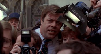 Movie still from “Splash” (1983), directed by Ron Howard – A man in a tie is surrounded by reporters and cameras; Close Up shot, Low angle