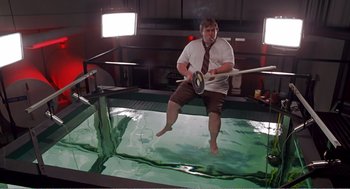 Movie still from “Splash” (1983), directed by Ron Howard – A man in a white shirt and brown shorts jumping in a pool of water; Wide shot, High angle
