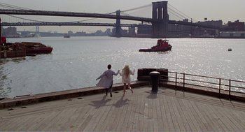 Movie still from “Splash” (1983), directed by Ron Howard – Two people are running on a pier near the water; Extreme Wide shot, High angle