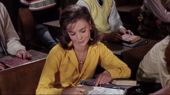 Movie still from “Splendor in the Grass” (1961), directed by Elia Kazan – A woman in a yellow shirt writing on a piece of paper; Medium shot, High angle
