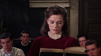 Movie still from “Splendor in the Grass” (1961), directed by Elia Kazan – A young woman reading a book in front of a young man; Medium shot, Low angle