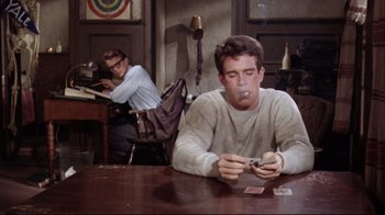 Movie still from “Splendor in the Grass” (1961), directed by Elia Kazan – A man smoking a cigarette while sitting at a table; Medium shot, Low angle