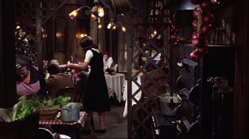 Movie still from “Splendor in the Grass” (1961), directed by Elia Kazan – A woman standing in front of a table with food on top of it; Wide shot, High angle
