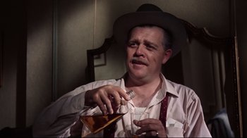 Movie still from “Splendor in the Grass” (1961), directed by Elia Kazan – A man wearing a hat and holding a glass of wine; Medium shot, Low angle
