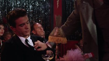 Movie still from “Splendor in the Grass” (1961), directed by Elia Kazan – Two men in suits are sitting at a table with a lamp on top of the table; Medium shot, Over the shoulder angle