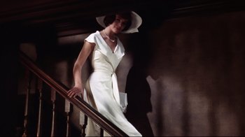 Movie still from “Splendor in the Grass” (1961), directed by Elia Kazan – A woman wearing a white dress and a hat standing at the top of a stair railing; Medium shot, Low angle