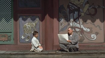 A man and a boy sitting on the ground with a computer