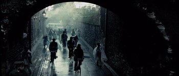 Movie still from “Spy Game” (2001), directed by Tony Scott – A group of people riding bikes down a street; Extreme Wide shot, High angle
