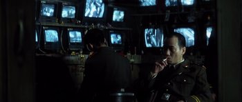 Movie still from “Spy Game” (2001), directed by Tony Scott – Two men are sitting in front of a television set; Medium shot, Over the shoulder angle