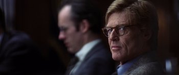 Movie still from “Spy Game” (2001), directed by Tony Scott – A man in a suit and a man in a suit and glasses; Close Up shot, Over the shoulder angle