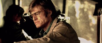 Movie still from “Spy Game” (2001), directed by Tony Scott – A person wearing glasses and a jacket; Close Up shot, Low angle
