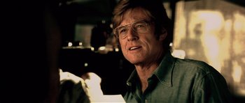 Movie still from “Spy Game” (2001), directed by Tony Scott – A person wearing glasses and a shirt; Close Up shot, Over the shoulder angle
