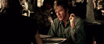 Movie still from “Spy Game” (2001), directed by Tony Scott – A man sitting at a table looking at papers; Close Up shot, Over the shoulder angle