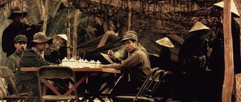 Movie still from “Spy Game” (2001), directed by Tony Scott – A man sitting at a table in front of a cake; Medium shot, Low angle