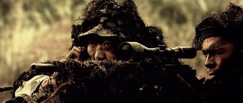 Movie still from “Spy Game” (2001), directed by Tony Scott – A man in a ghillie suit with a rifle in his hand; Close Up shot, Low angle