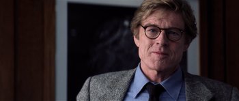 Movie still from “Spy Game” (2001), directed by Tony Scott – A person wearing a suit and glasses; Close Up shot, Over the shoulder angle