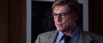 Movie still from “Spy Game” (2001), directed by Tony Scott – A person wearing glasses and a suit; Close Up shot, Over the shoulder angle